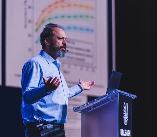 Ethan Mollick speaking with open hands at a lectern at UNLEASH America 2024.