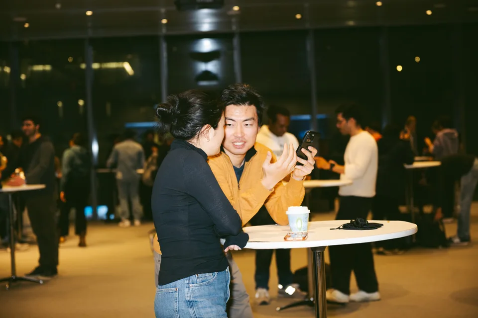 Two attendees chatting beside a standing table with refreshments.